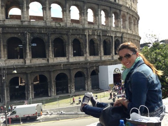 happy razan masri sitting on a cliff looking at the beautiful colloseum in jeans and converse