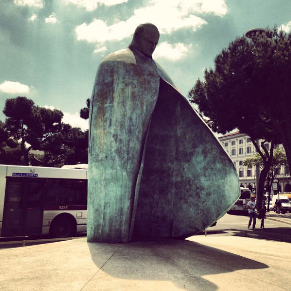 sunny day, a big welcoming statue with its shadowing in the middle of rome 