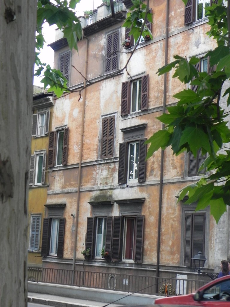 photo of the architecture of a building by the river with its orange vintage paint and retro windows in rome