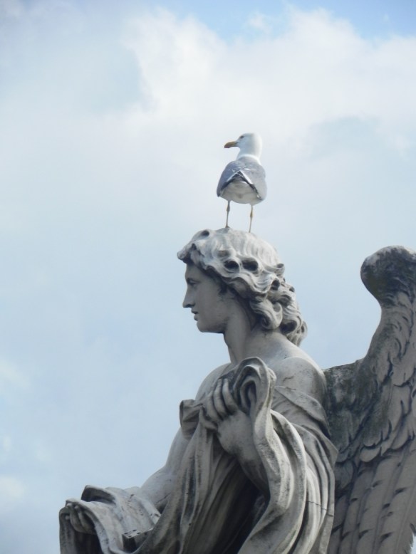 a bird is resting on one of the statues head at the st angelo all white with blue sky