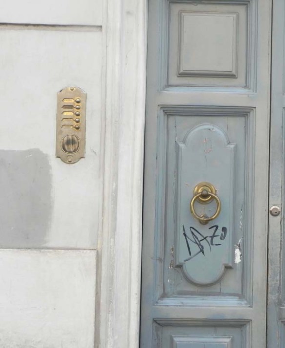 A very old door bell with a blue door 