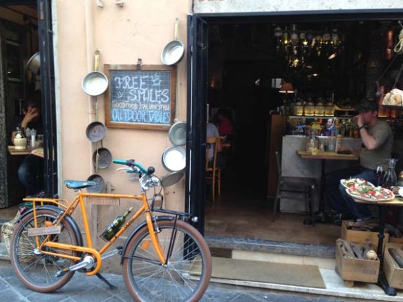 a retro vintage hip looking bicycle lying on a wall next to a shop at the campo de'fiori
