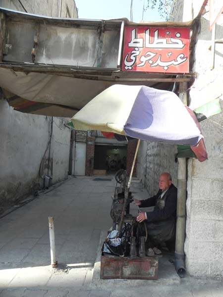 An old man still making shoes and asking for money at albalad downtown Amman