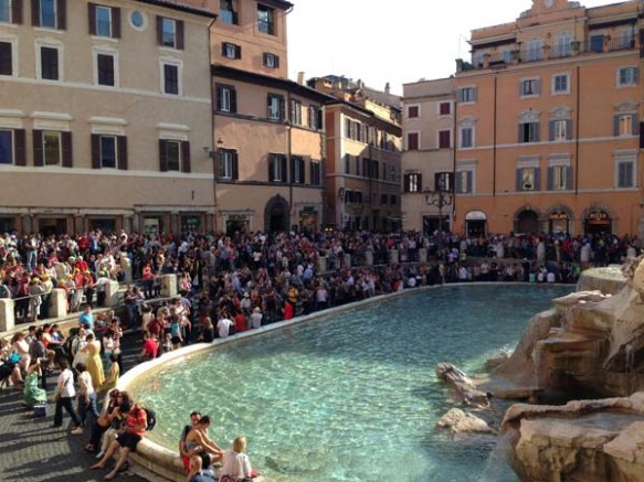 Tourists and italians at the Fontana de trevi making wishes and watching the beautiful fountain