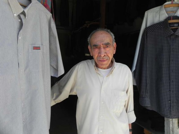 Portrair of An old man still working at his own menswear shop downtown albalad