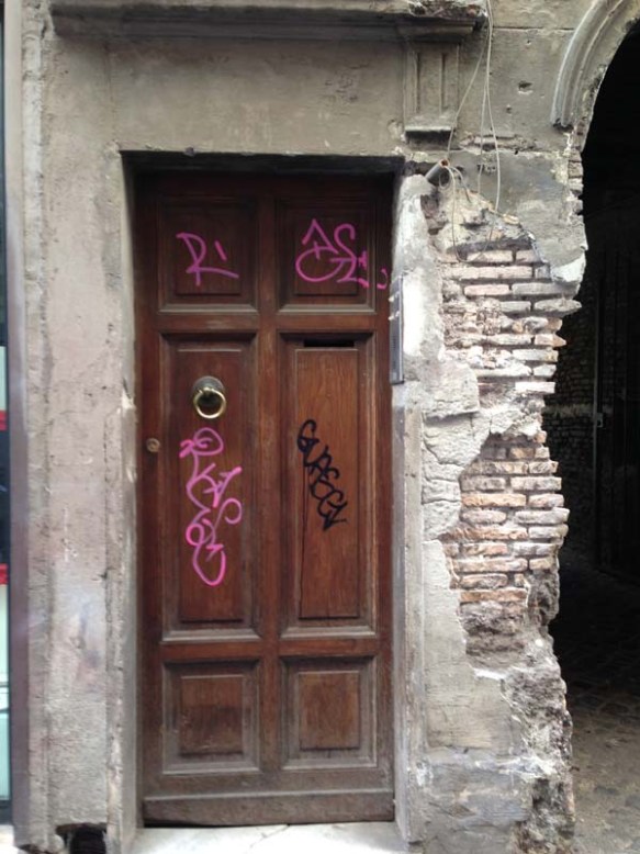 A very old stone wall with a very old vintage brown door italian roman