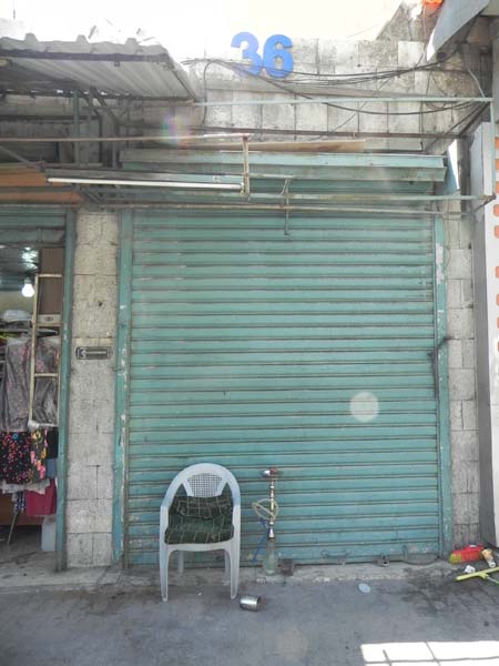 A closed green garage door with a shisha argeeleh or hubblly bubbly and an empty chair infront of it albalad amman 