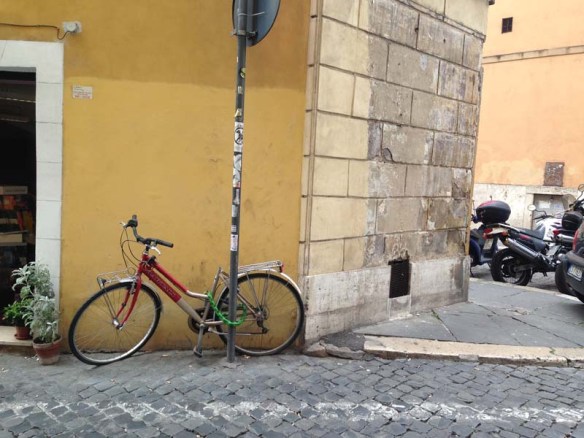 A beautiful yellow mustard wall with a bicycle leaning on it in rome