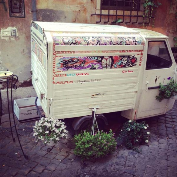 a small white bus carrying plants and flowers as an art piece in the streets on navona rome