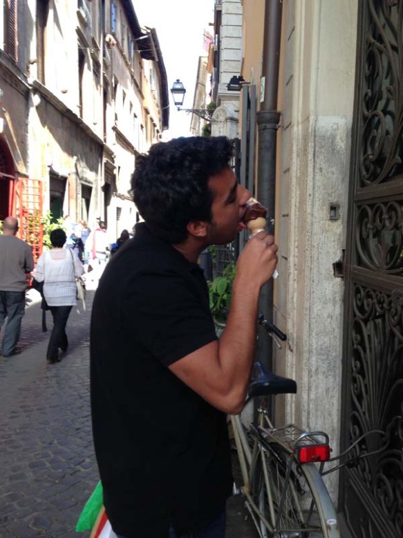 a guy licking icecream infront of a gelateria