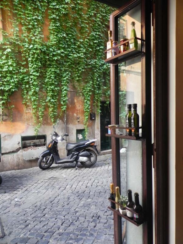 the front view of baguetteria del fico overlooking plants on street and a motobike