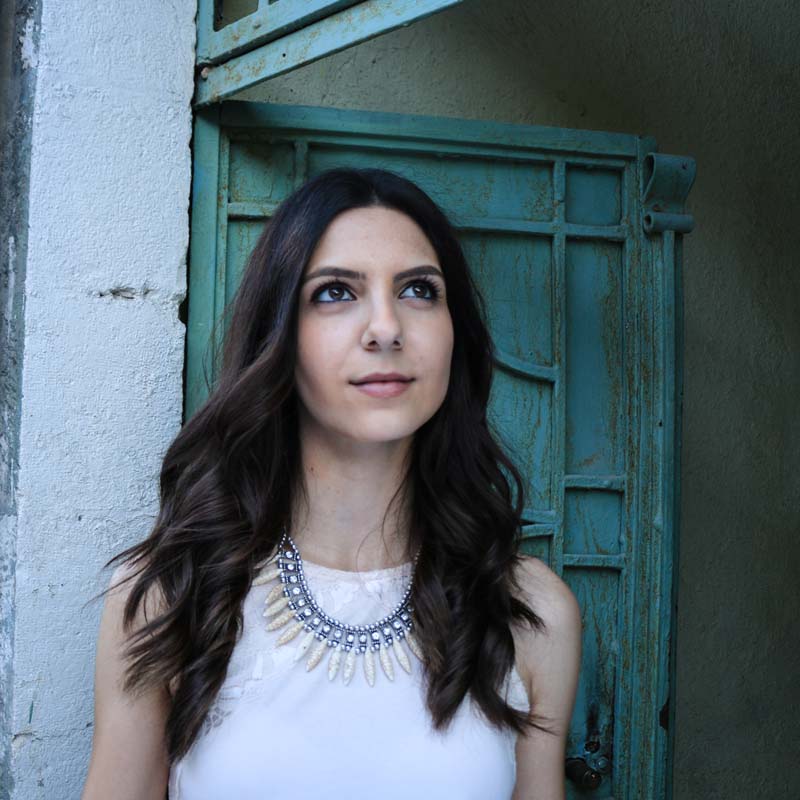 A photograph of a female model from modelicious agency jordan looking into the sky with an antique green door behind her