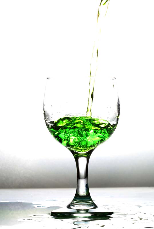 A picture of a glass being filled with green water liquid 