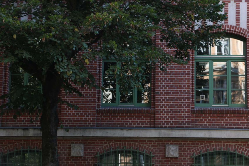 Red brick building with green windows and tree in berlin